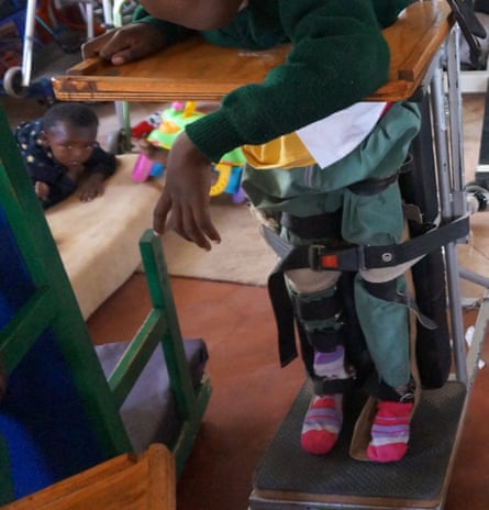 A child held in a standing position as part of physical therapy at Compassionate Hands