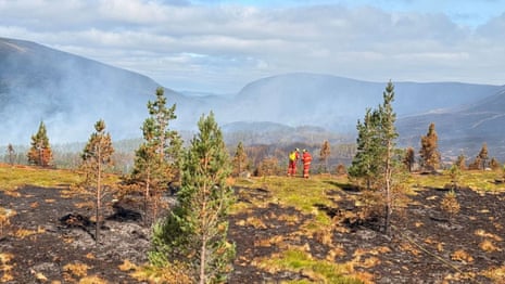Two firefighters at Cairngorms national park where smoke can be seen in the distance.