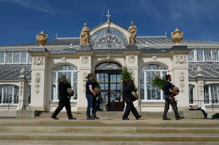 Horticulturalists carry saplings past the entrance to the Temperate House at Kew Gardens.