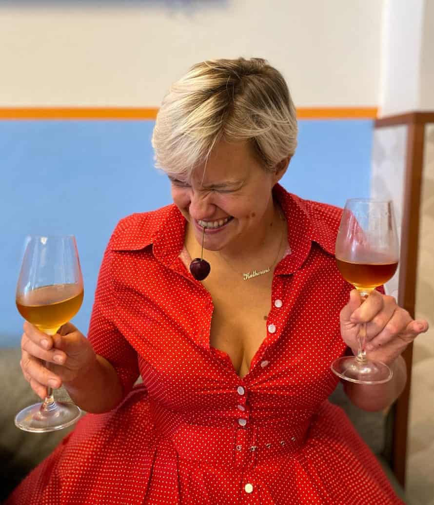 Katherine Petty with a cherry in her mouth holding two wine glasses