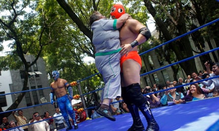 An employee of Mexico’s health ministry embraces a wrestler during an exhibition bout to mark the start of a campaign to fight obesity in Mexico City.