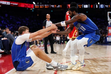 Mavericks guard Kyrie Irving helps teammate Cooper Flagg to his feet during Sunday’s NBA pre-season game against the Rockets at the Venetian Arena in Macau.