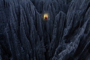 Climber, lit by torch, scaling the dark rocks