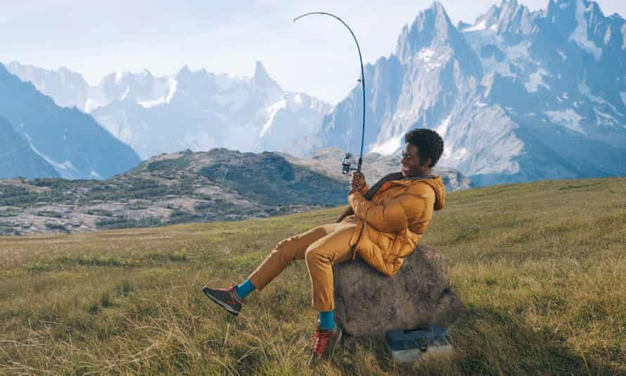 Man holding fishing rod sitting on a rock.