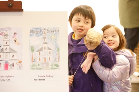 A boy and his sister stand in front of a drawing of a church