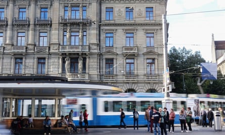 Pedestrians wait at a tram stop in Zurich, Switzerland. Efficient public transport systems are needed.