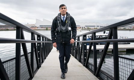 Rishi Sunak wearing a life jacket, walking up a ramp from a boat
