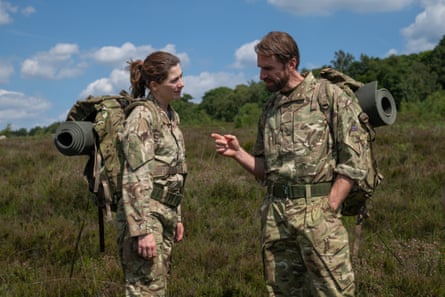 Joseph Fiennes and Jodie Whittaker talking outside wearing combat gear and carrying rucksacks