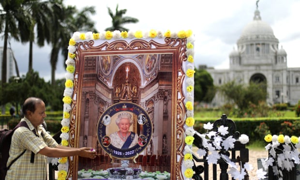 A man offers flower petals in front of a picture of late Queen Elizabeth II near the Victoria memorial in Kolkata.