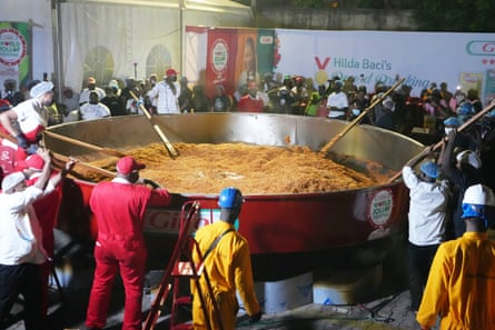 People stir a giant pot with rice in it