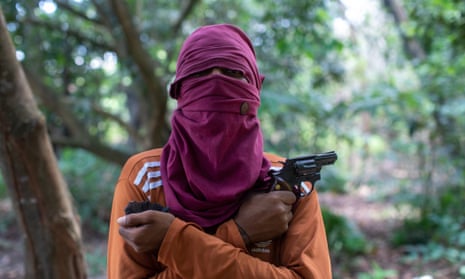 A young member of the Brazilian crime group, the First Capital Command, shows off his revolver on the outskirts of a city in the Amazon.