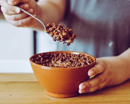 Hand holding a spoon, eating a bowl of choco Krispies