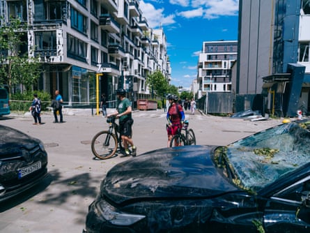 Two cyclists stand near the damaged buildings