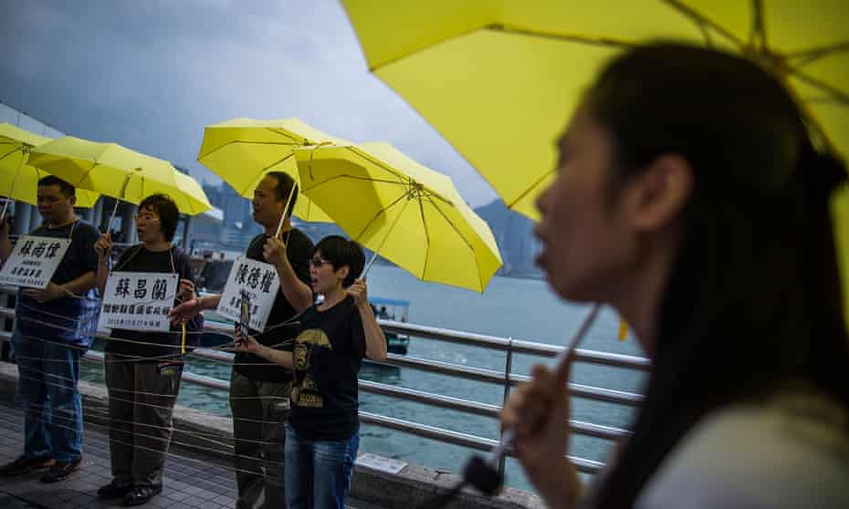 people holding yellow umbrellas on  Tsim Sha Tsui Pier  in  Hong Kong