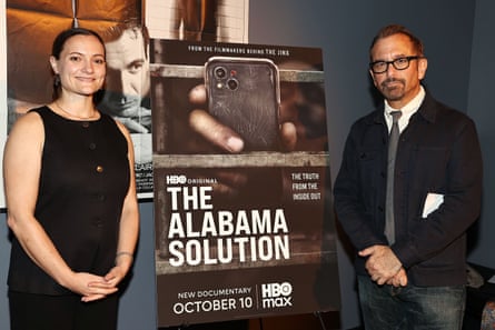 Two people flank a movie poster on an easel.