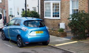 electric car being charged in street with lead from owners home electric car being charged in street with lead from owners home