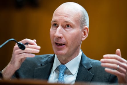 a man in suit speaking into microphone, hands gestured