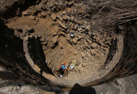 An Indian woman tries to collect drinking water in a dried-up well at Bhakrecha Pada in Thane district in Maharashtra state, India