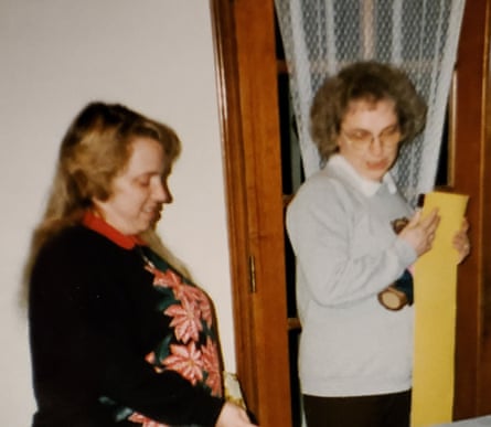 Two women standing inside a house with one wearing a grey sweater and the other a black one