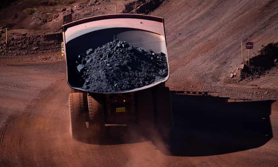 A rear view of a loaded iron ore truck on a dirt road