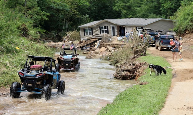 ATV drivers at a home torn from its foundations during flooding and left in the middle of the road, along Bowling Creek, Kentucky.