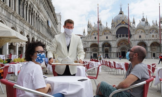 A waiter serves two tourists at the outdoor tables of the ‘Caffe Quadri’ on St Mark’s square.