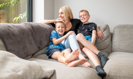 Rachael sitting at home on a sofa with Alfie, seven, and Arthur, 10.