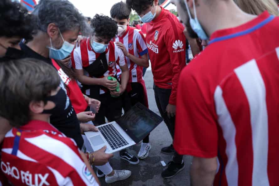 Atlético Madrid fans watch the game on a laptop from outside the stadium.
