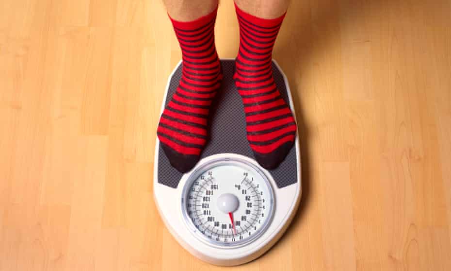 Man in red and black stripy socks standing on bathroom scales