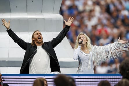 A man and a woman performing on stage with their arms raised
