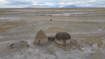 Two round clay houses with a barren landscape beyond.