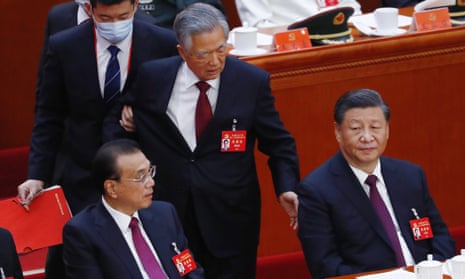 China's former president Hu Jintao is led out as President Xi Jinping (right) looks on.