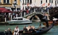 People protest on a bridge with people in a gondola taking photos on their phone