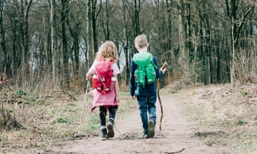 a boy and a girl hiking with sticks and backpacks