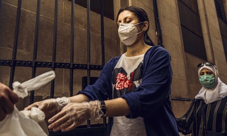 A volunteer wearing a protective face mask hands out free food rations for the poor people in Barcelona.