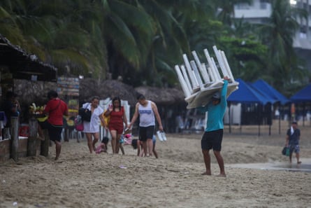 A man removes tables off a beach as Hurricane Otis barrels towards Acapulco, Mexico
