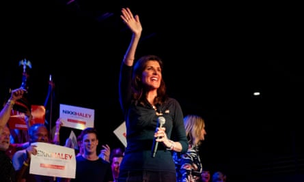 a woman in a dark shirt waves with her arm extended high and a crowd behind her