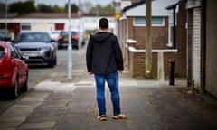 Man standing in a residential street facing away from the camera.