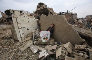 A boy sits with belongings he collected from the rubble of his house in the neighbourhood of al-Arkoub