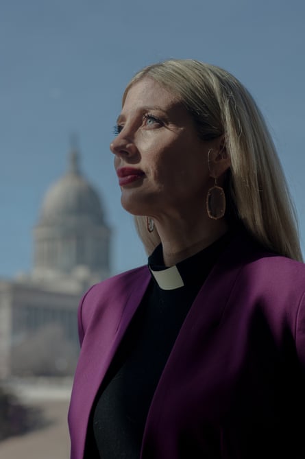 portrait of woman wearing pink suit with white building in the back