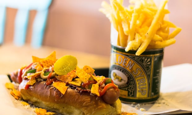 Hotdog, loaded with toppings and nachos, and a side order of fries in a syrup tin, from Hogwurst, Cardiff