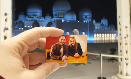Aya holds up a picture of herself and her brother Hussein in front of the Sheikh Zayed Grand Mosque in Abu Dhabi