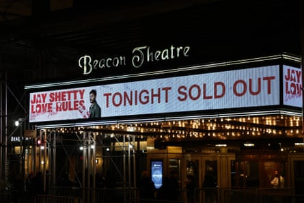 The awning of a movie theater, with letters spelling Beacon Theatre on the top, and red letters on a white background below spelling ‘Tonight Sold Out’. The rest of the image is dark and blurry, indicating lights being reflected in rain.
