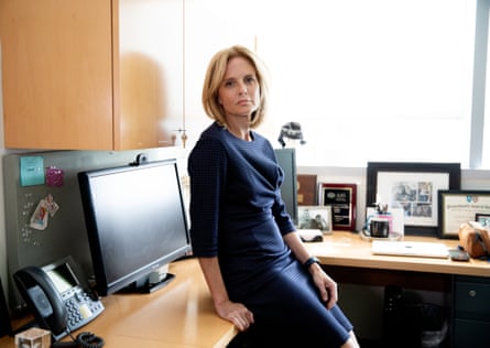 Carrie Cunningham, MD, in her office, sitting on a desk