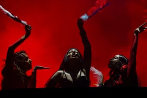 Lady Gaga with two dancers against a dark red background