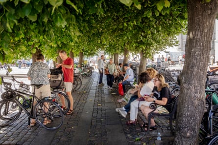 People sit on benches in the shade
