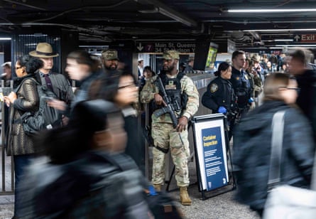 officers with big guns amid blurry images of commuters walking by