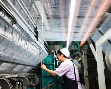 A worker operates machinery on a production line in a warp knitting workshop in Lianyungang, Jiangsu Province of China.