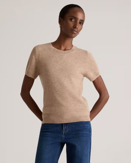 woman wearing beige shirt and jeans with hands behind back