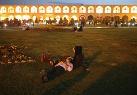 A couple lies in the Naqsh-e Jahan Square in Isfahan, surrounded by buildings from the Safavid era.